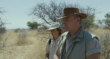 Movie still from “Safari” (2016), directed by Ulrich Seidl – A man and a woman wearing hats in a field; Medium shot, Over the shoulder angle