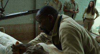 Movie still from “Safari” (2016), directed by Ulrich Seidl – A man in brown shirt and tie cutting paper; Close Up shot, Over the shoulder angle