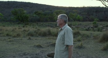 Movie still from “Safari” (2016), directed by Ulrich Seidl – An older man standing in the middle of a field; Medium shot, Over the shoulder angle
