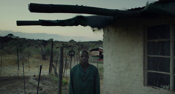 Movie still from “Safari” (2016), directed by Ulrich Seidl – A man standing in front of a building; Medium shot, Low angle