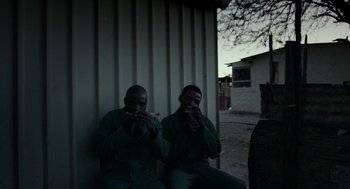 Movie still from “Safari” (2016), directed by Ulrich Seidl – A couple of men sitting next to each other on a bench; Medium shot, Low angle