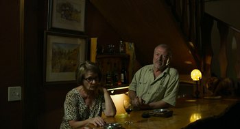 Movie still from “Safari” (2016), directed by Ulrich Seidl – A man and a woman sitting at a table in a room; Medium shot, Over the shoulder angle