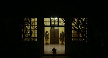 Movie still from “Safari” (2016), directed by Ulrich Seidl – A person laying on the ground in front of a door way; Extreme Wide shot, Low angle