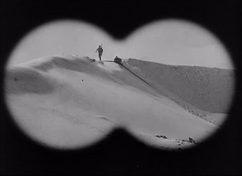 Movie still from “Sahara” (1943), directed by Zoltan Korda – A person standing on top of a snow covered slope; Extreme Wide shot, Low angle