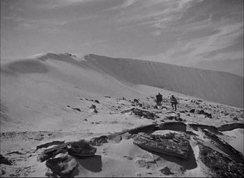 Movie still from “Sahara” (1943), directed by Zoltan Korda – Two people are standing on a snowy hill; Extreme Wide shot, Low angle