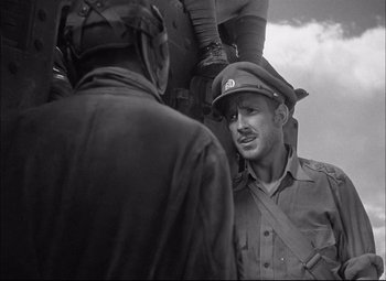 Movie still from “Sahara” (1943), directed by Zoltan Korda – A black and white photo of a man in a military uniform; Medium shot, Low angle