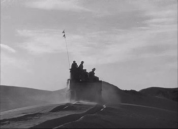 Movie still from “Sahara” (1943), directed by Zoltan Korda – A group of men riding on the back of a truck; Extreme Wide shot, High angle
