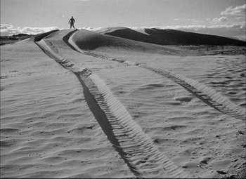 Movie still from “Sahara” (1943), directed by Zoltan Korda – A person standing on top of a sandy beach; Extreme Wide shot, High angle