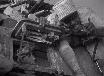 Movie still from “Sahara” (1943), directed by Zoltan Korda – An old photo of a man working on a machine; Medium shot, Low angle