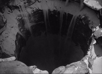 Movie still from “Sahara” (1943), directed by Zoltan Korda – A black and white photo of a hole in the ground; Extreme Wide shot, Overhead angle