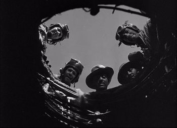 Movie still from “Sahara” (1943), directed by Zoltan Korda – A black and white photo of a group of men in hats; Medium shot, Low angle