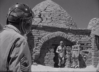 Movie still from “Sahara” (1943), directed by Zoltan Korda – A black and white photo of a man and two men in military uniforms; Medium shot, Low angle