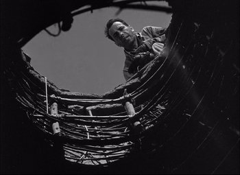 Movie still from “Sahara” (1943), directed by Zoltan Korda – A man standing inside of a large metal structure; Medium shot, Low angle