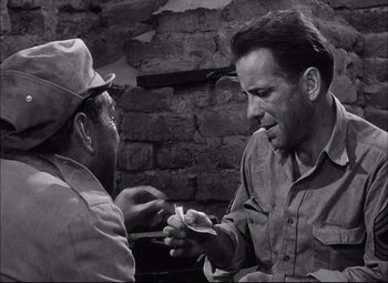 Movie still from “Sahara” (1943), directed by Zoltan Korda – Two men are talking to each other in front of a brick wall; Close Up shot, Over the shoulder angle