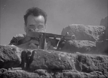 Movie still from “Sahara” (1943), directed by Zoltan Korda – A man is holding a gun in his hands; Close Up shot, Low angle