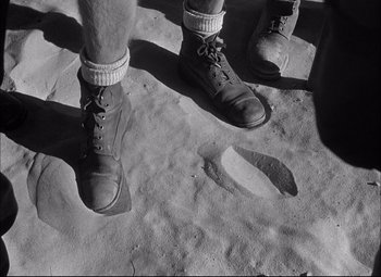 Movie still from “Sahara” (1943), directed by Zoltan Korda – A man standing on top of a sandy beach; Close Up shot, High angle