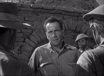 Movie still from “Sahara” (1943), directed by Zoltan Korda – A black - and - white photo of a man in a hat; Medium shot, Over the shoulder angle