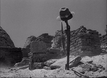 Movie still from “Sahara” (1943), directed by Zoltan Korda – An old photo of a hat and a knife in the desert; Wide shot, Low angle