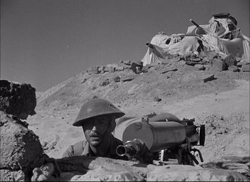Movie still from “Sahara” (1943), directed by Zoltan Korda – An old photo of a man with a gun in the desert; Medium shot, Low angle