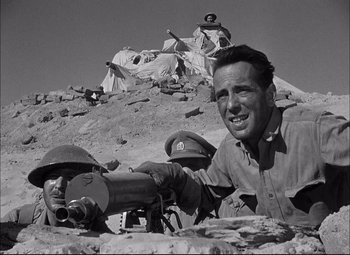 Movie still from “Sahara” (1943), directed by Zoltan Korda – An old black and white photo of a man with a gun; Medium shot, Low angle