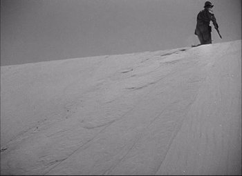 Movie still from “Sahara” (1943), directed by Zoltan Korda – A person is standing on a snowy hill; Extreme Wide shot, High angle