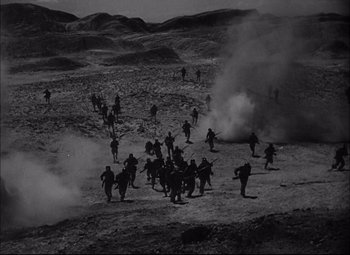 Movie still from “Sahara” (1943), directed by Zoltan Korda – A black and white photo of a group of soldiers in the desert; Extreme Wide shot, High angle