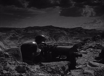 Movie still from “Sahara” (1943), directed by Zoltan Korda – A black - and - white photo of a man in a helmet and a gun; Wide shot, High angle