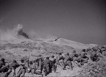 Movie still from “Sahara” (1943), directed by Zoltan Korda – A black and white photo of a group of men sitting on top of a hill; Extreme Wide shot, High angle