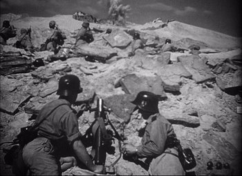 Movie still from “Sahara” (1943), directed by Zoltan Korda – A black and white photo of men in military gear; Wide shot, High angle