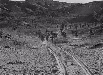 Movie still from “Sahara” (1943), directed by Zoltan Korda – A black and white photo of a group of people riding horses; Extreme Wide shot, High angle