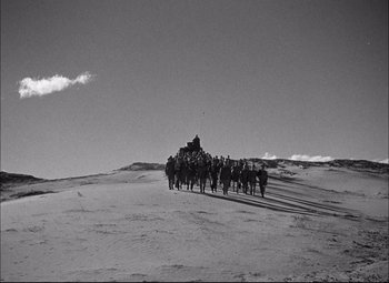 Movie still from “Sahara” (1943), directed by Zoltan Korda – A black and white photo of a group of people on horses; Extreme Wide shot, High angle
