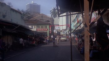 Movie still from “Saint Jack” (1979), directed by Peter Bogdanovich – A street scene with people walking on the sidewalk and cars driving down the street; Extreme Wide shot, High angle