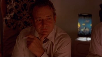 Movie still from “Saint Jack” (1979), directed by Peter Bogdanovich – A man in a white dress shirt is smoking a cigarette; Close Up shot, Low angle