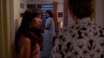 Movie still from “Saint Jack” (1979), directed by Peter Bogdanovich – A woman standing in front of two other women in a room; Medium shot, Over the shoulder angle