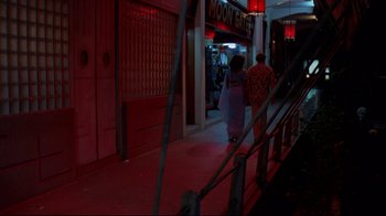 Movie still from “Saint Jack” (1979), directed by Peter Bogdanovich – Two people walking down a street at night; Wide shot, High angle