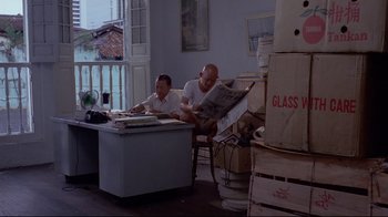Movie still from “Saint Jack” (1979), directed by Peter Bogdanovich – Two men sitting at a table in a room; Wide shot, High angle