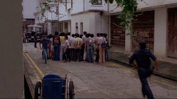 Movie still from “Saint Jack” (1979), directed by Peter Bogdanovich – A group of people standing on the side of the street; Extreme Wide shot, High angle