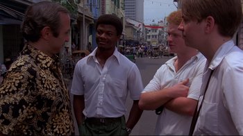 Movie still from “Saint Jack” (1979), directed by Peter Bogdanovich – A group of men standing on the side of the street; Medium shot, Over the shoulder angle