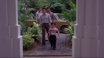 Movie still from “Saint Jack” (1979), directed by Peter Bogdanovich – A group of people walking down a road; Wide shot, Low angle