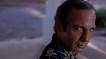 Movie still from “Saint Jack” (1979), directed by Peter Bogdanovich – A person wearing a floral shirt; Close Up shot, Low angle