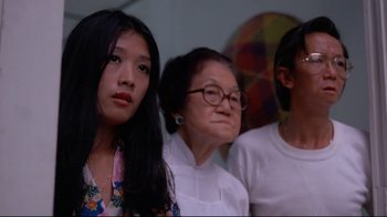 Movie still from “Saint Jack” (1979), directed by Peter Bogdanovich – A group of people sitting next to each other in a room; Close Up shot, Low angle