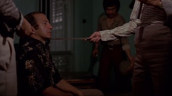 Movie still from “Saint Jack” (1979), directed by Peter Bogdanovich – A man is being whipped by another man in front of another man; Medium shot, Over the shoulder angle