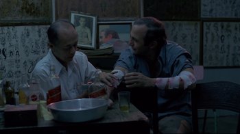 Movie still from “Saint Jack” (1979), directed by Peter Bogdanovich – Two men sitting at a table with a bowl of food; Medium shot, High angle