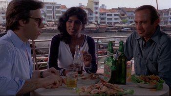 Movie still from “Saint Jack” (1979), directed by Peter Bogdanovich – A woman sitting at a table with a plate of food; Medium shot, High angle