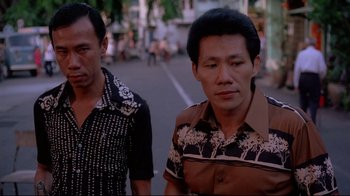 Movie still from “Saint Jack” (1979), directed by Peter Bogdanovich – Two men walking down a street in a city; Close Up shot, Low angle