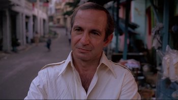 Movie still from “Saint Jack” (1979), directed by Peter Bogdanovich – A person wearing a white shirt; Close Up shot, Over the shoulder angle