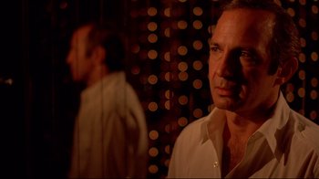 Movie still from “Saint Jack” (1979), directed by Peter Bogdanovich – A man standing in front of a wall of lights; Close Up shot, Low angle