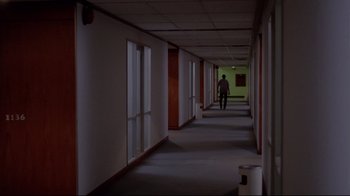 Movie still from “Saint Jack” (1979), directed by Peter Bogdanovich – A man walking down a hallway in a building; Extreme Wide shot, High angle