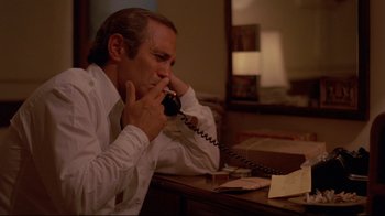 Movie still from “Saint Jack” (1979), directed by Peter Bogdanovich – A man sitting at a desk talking on a phone; Close Up shot, High angle