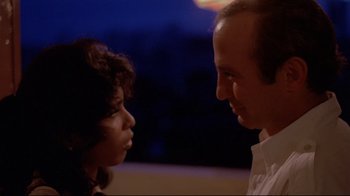 Movie still from “Saint Jack” (1979), directed by Peter Bogdanovich – A man and a woman looking at each other in front of a night sky; Close Up shot, Low angle